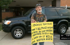Man forced to hold 'IDIOT' sign outside police station