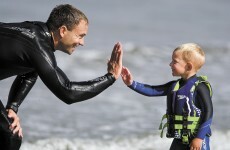 Three-year-old surfer kid rides waves and gives high five