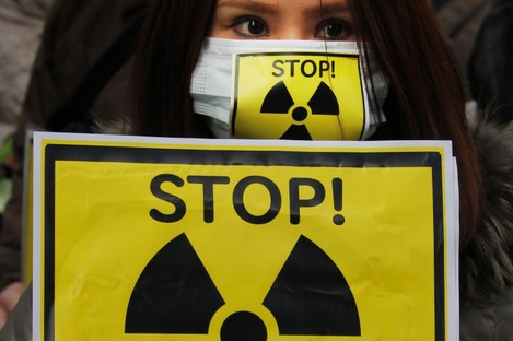 A protester holds a placard during an antinuclear rally in Tokyo earlier today, as staff were once again evacuated from the Fukushima I power plant.