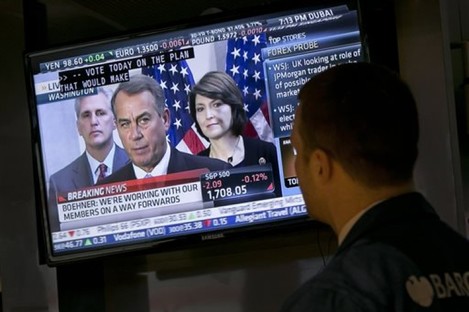 Specialist Frank Masiello watches a television monitor on the floor of the New York Stock Exchange showing a Washington news conference by House Speaker John Boehner