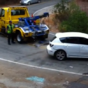 Tow truck driver watches helplessly as car rolls downhill