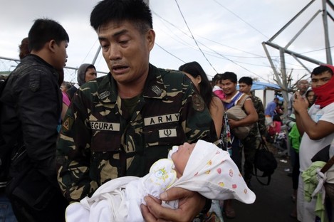 A soldier carries one-day-old baby Ian Daniel Honrado to a waiting military transport plane at Tacloban city, central Philippines. 