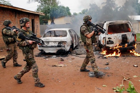 French troops patrol past two Seleka, the alliance of mostly Muslim rebel groups, vehicles set on fire by Christian mobs in Bangui.