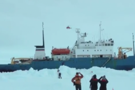 Passengers watch as a helicopter flies over the stranded ship