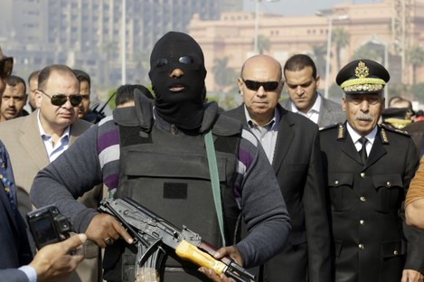 An Egyptian masked policeman guards Cairo's state security chief, Osama al-Saghir, third right, as he visits Tahrir Square.