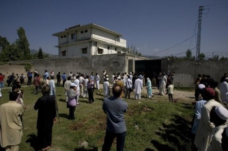 Local people and media gather outside the wall of the compound and house where bin Laden was killed.