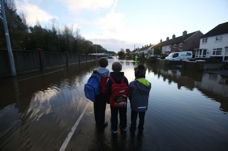 Children look at flood water on Nutgrove Avenue in Dublin on their way to school on Friday. 