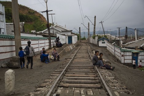 File Photo: North Korean people rest next to the railroad tracks in a town in North Korea's North Hamgyong province
