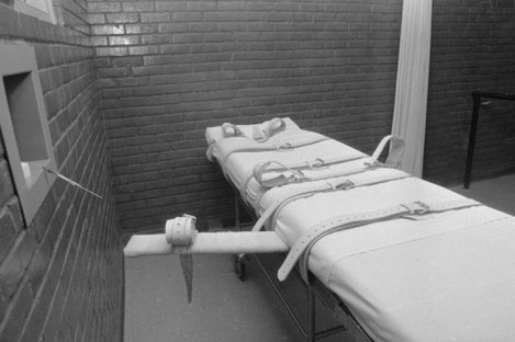 A gurney used for lethal injection executions in Hunstville, Texas - an observation window and an intravenous needle is visible on the left wall.