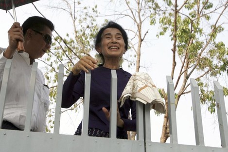 Aung San Suu Kyi smiles over the gates of her residence where she was under house arrest. 