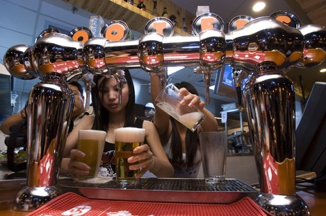 Waitresses fill beer glasses at the Beijing outlet for Hooters
