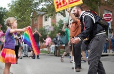 A little girl defiantly held a rainbow flag throughout a preacher's anti-gay rant