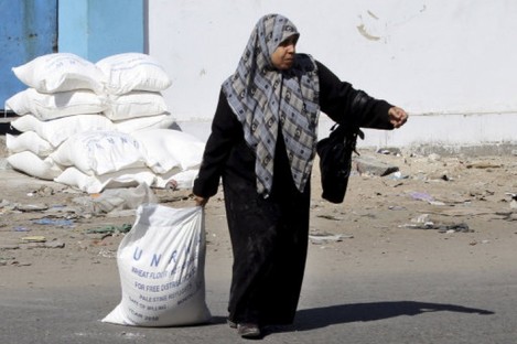 A Palestinian woman drags a sack of flour at a UN food distribution centre at Shati refugee camp.