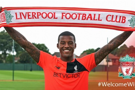Wijnaldum holds up the Liverpool scarf at Melwood today. 