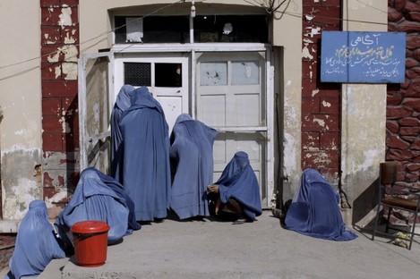 File photo: Afghan women peek inside a hospital while she and others wait for an employee to let them enter, on the outskirts of Kabul, Afghanistan
