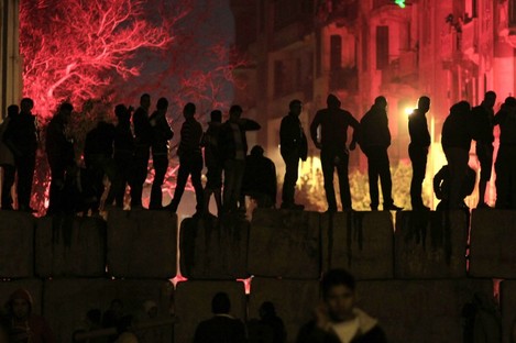Egyptian protesters stand on a cement block barrier separating the interior ministry from Tahrir Square, Cairo last night.