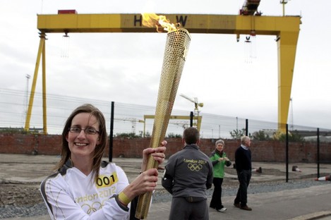 Karen Marshall, the first torch bearer from Northern Ireland, poses with the Olympic torch in front of Harland & Wolff shipyard this morning.