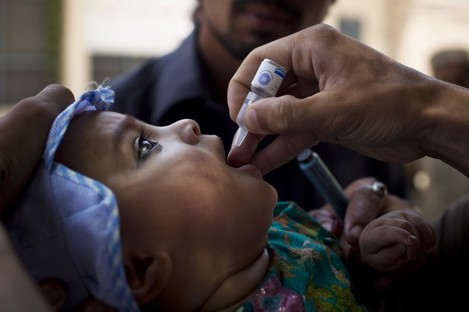 A Pakistani child is given a polio vaccination by a health worker
