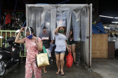 Women exit from a disinfecting area after buying food at a public market in Quezon City in the Philippines. 