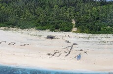 Men rescued from uninhabited Pacific island after writing SOS in sand