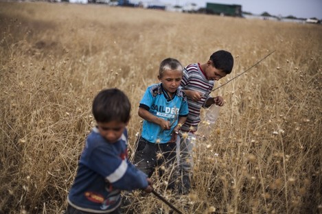 Syrian boys play near a refugee camp on the border with Turkey