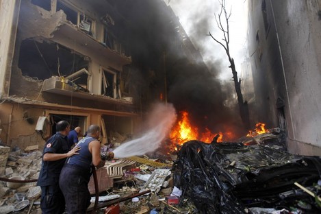 Lebanese firefighters extinguish burning cars at the scene of an explosion in the mostly Christian neighborhood of Achrafiyeh, Beirut.