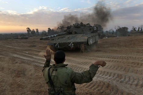 An Israeli soldier guides a tank to a new position at a staging area near the Israel Gaza Strip Border, southern Israel yesterday.