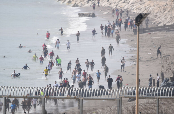 Hundreds of people swim round barriers and enter North African Spanish territory from Morocco