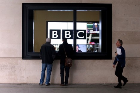 Staff walk past television screens at the BBC's Headquarters, New Broadcasting House, in central London.