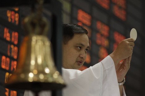 A Catholic priest makes an offertory during a mass before the start of the first day of trading at Philippine Stock Exchange.