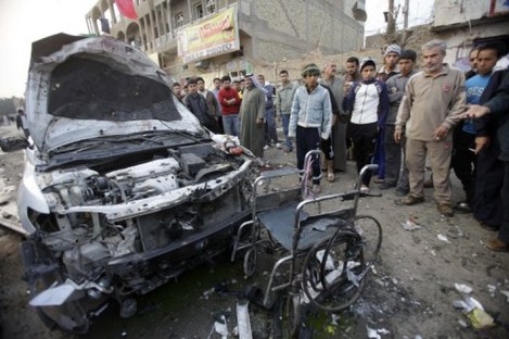 People inspect a destroyed car and a wheelchair at the scene of a car bomb attack Baghdad, Iraq, today.