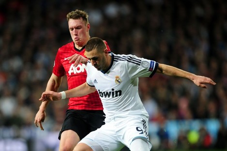 Manchester United's Phil Jones and Real Madrid's Karim Benzema (right) battle for the ball during the UEFA Champions League round of 16 match at Santiago Bernabeu.
