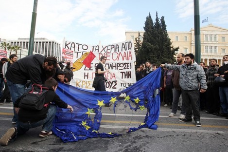 Young Greek people burn an EU flag late last month outside parliament in Athens at protests against education cuts.