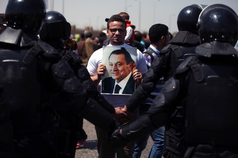 A supporter holds a photo of Egypt's ousted president Hosni Mubarak as riot police stand guard outside a courtroom in Cairo, Egypt, earlier this week.