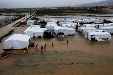 Syrian refugees make their way in flooded water at a temporary refugee camp, in the eastern Lebanese Town of Al-Faour
