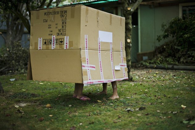 Children play in garden with cardboard box