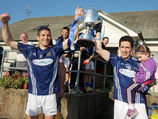Sean Kelly and his teammate Mark Blake with his two-year-old daughter Lily lift the trophy