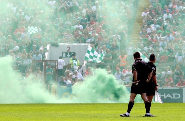 Match officials look on at a flare