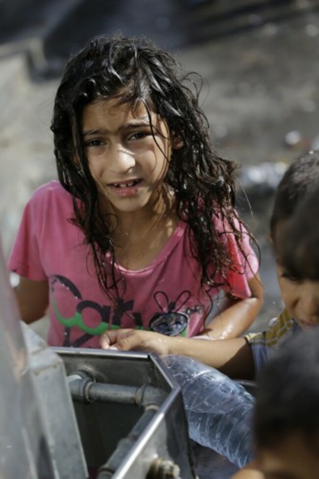 A displaced Palestinian child collects water, at the Abu Hussein U.N. school, in Jebaliya refugee camp, northern Gaza Strip