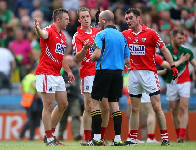 Cork players surround referee Cormac Reilly