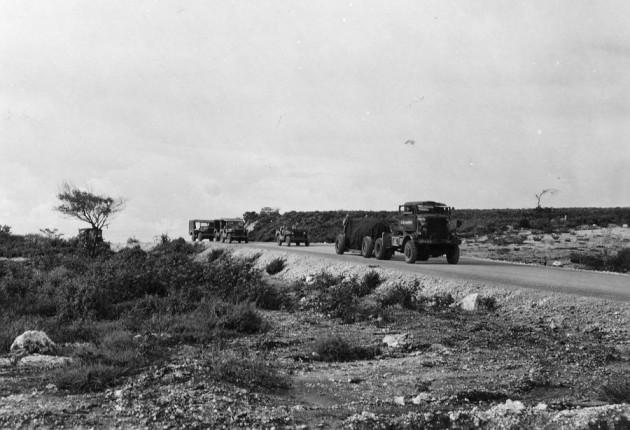 the-bomb-is-then-escorted-to-the-nearby-north-field-airbase-on-tinian-shrouded-in-tarp