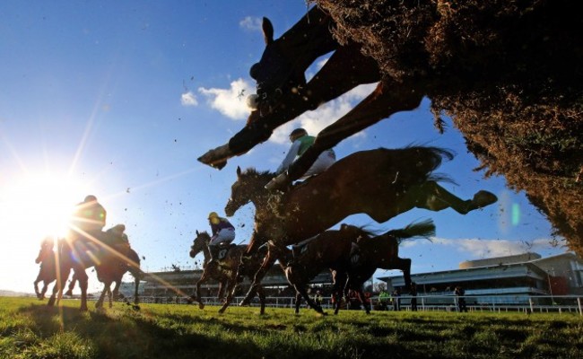 Riders and runners clear a hurdle