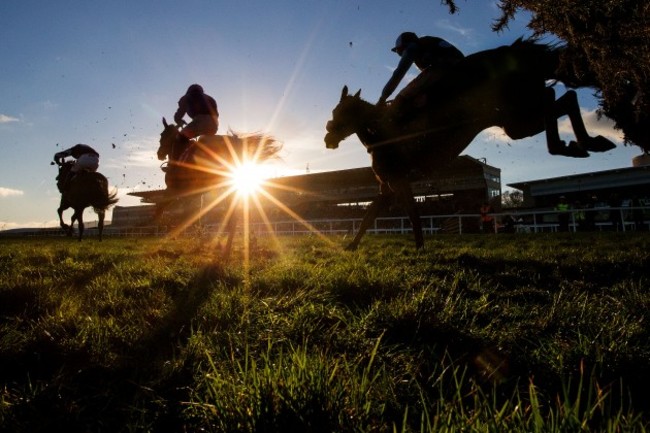 Riders and runners clear a hurdle