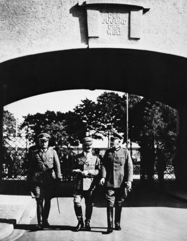 here-we-see-hitler-center-and-two-aides-enter-the-olympic-village-for-an-inspection-the-gateway-inscription-reads-to-the-youth-of-the-world