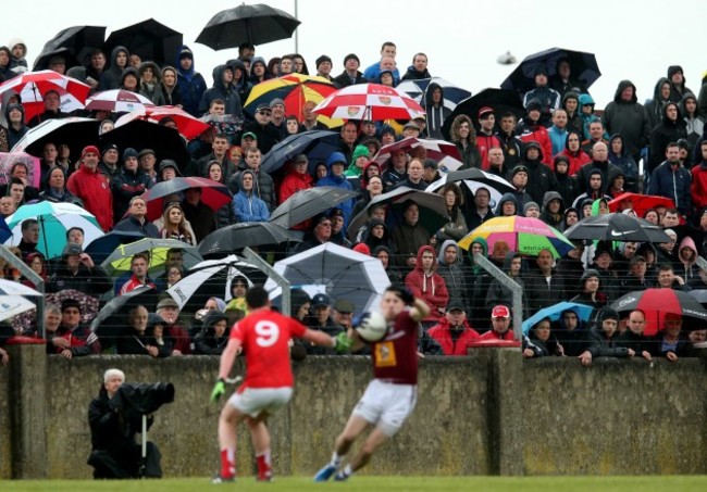 Spectators shelter under umbrellas during the game