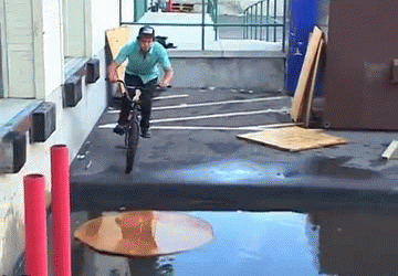 guy-rides-bike-over-puddle-on-cardboard