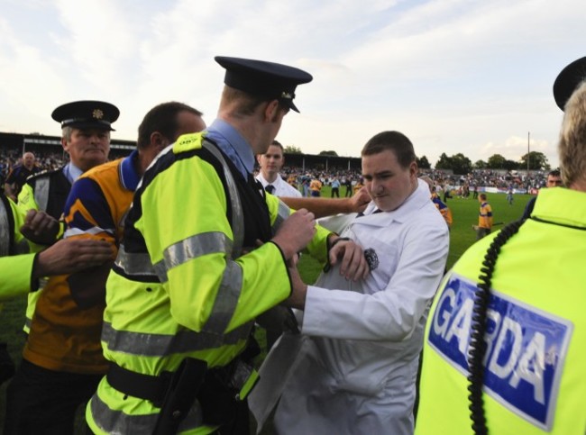 A match umpire is escorted from the pitch