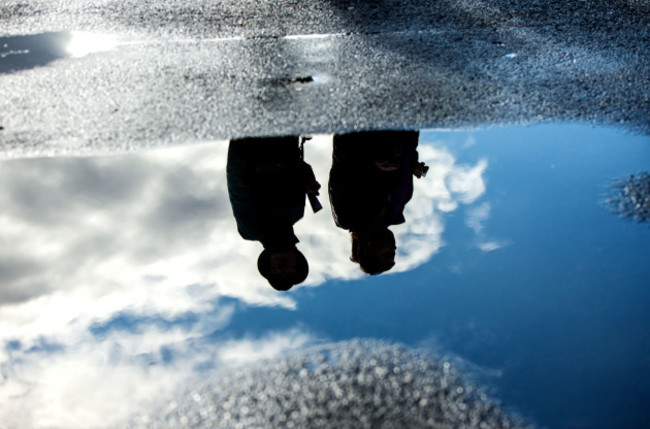 A view of punters reflected in a puddle