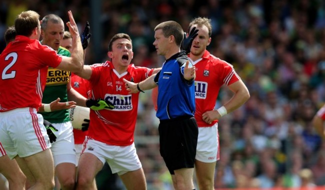 Cork players surround referee Padraig Hughes as he awards a penalty to Kerry