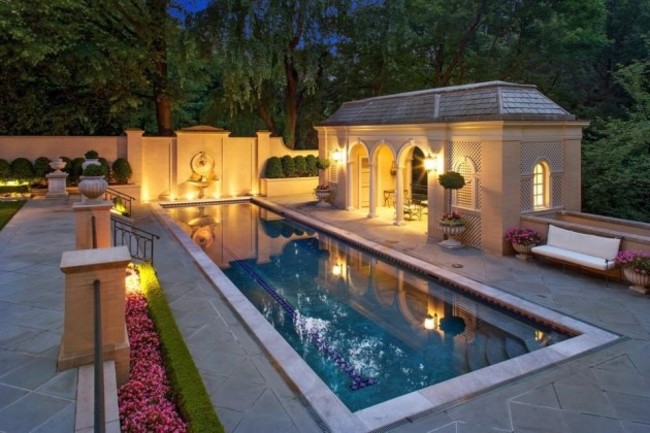 theres-an-indoor-pool-as-well-as-an-adjacent-poolhouse-among-an-immaculately-landscaped-backyard-surrounded-by-greenery